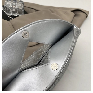 Close-up of woven silver handbag featuring internal magnetic snap closure and texture