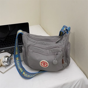 Versatile grey nylon multi-pocket crossbody bag with a wide decorative woven strap