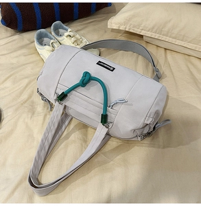 Dettaglio borsa da viaggio grigia in nylon con corda decorativa annodata verde sul davanti