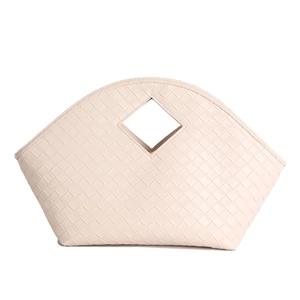 Macro detail of beige woven leather handbag with intricate square pattern and diamond handle