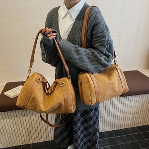 Sac Boston en daim marron avec bandoulière en cuir porté en travers par un mannequin chic