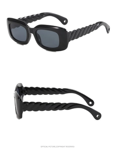 Close-up of black thick square sunglasses with unique twisted braid temple design