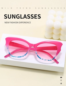Detail shot of pink cat-eye sunglasses with blue tortoiseshell lower frame on white stand