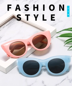 Fashionable oversized cat eye sunglasses in pink and light blue on marble surface