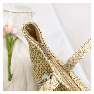 Detail of the high-quality metal zipper and hand-woven straw texture on a beige tote bag