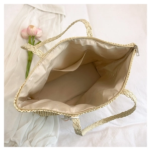 Internal view of straw tote bag showing zipper closure, lining, and pocket for storage