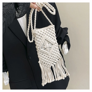 Detail of white hand-woven straw crossbody bag with diamond pattern and fringe tassels