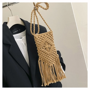 Detailed macro of bohemian hand-woven straw bag with tassels for beach vacation style