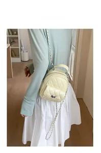 Cream quilted mini backpack with silver chain strap shown on model in a soft lifestyle setting
