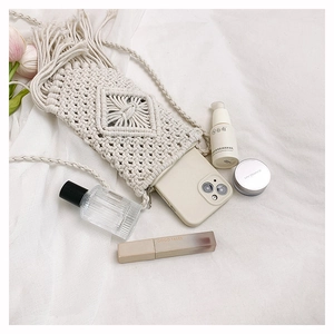 Détail de pochette téléphone bohème en coton tressé avec franges et bandoulière sur tissu