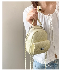 Detail of light yellow mini quilted backpack featuring silver twist lock and chain handle