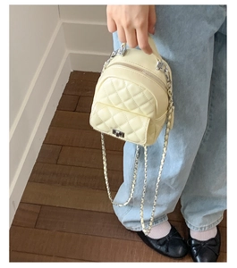 Detailed view of beige quilted mini backpack with silver chain strap and metal turn-lock