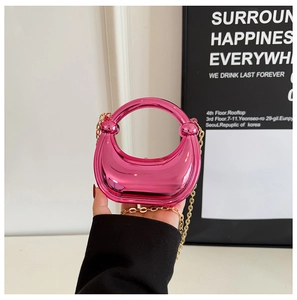 Macro detail of glossy magenta mini evening bag with round handle and gold chain strap