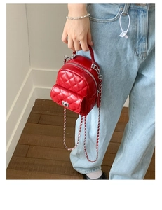 Macro detail of red quilted leather mini backpack with metal handle and silver clasp