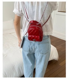 Detail of red quilted mini backpack with shiny finish and silver chain strap for women