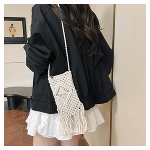 Detailed close-up of handmade cream woven crossbody bag with bohemian tassel and texture