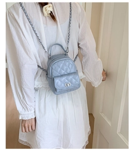 Detail of light blue quilted mini backpack with silver chain strap and metal turn-lock