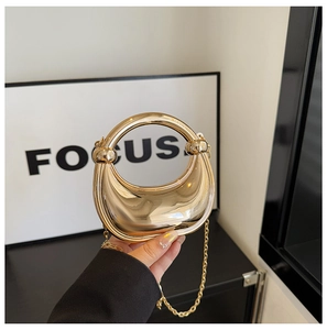 Detail of gold mirror acrylic moon evening bag with integrated circular top handle