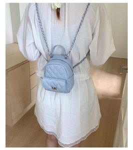 Detail of light blue quilted mini backpack with silver metal twist lock and chain straps