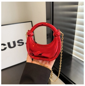 Detail of red acrylic crescent clutch with round handle and gold chain strap