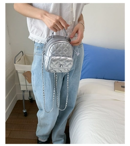 Detail of silver quilted mini backpack featuring metallic texture and chain strap