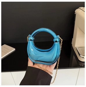 Macro view of bright blue mirror finish clutch bag with golden chain strap detail