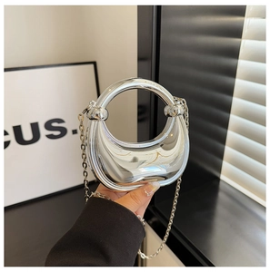 Close-up of a silver crescent moon evening bag with mirror finish and circular handle