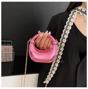 Detail of metallic pink crescent bag with round handle and gold chain strap
