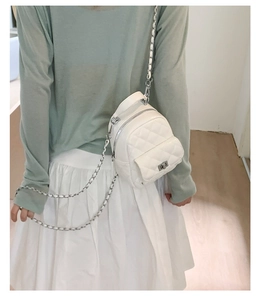 Rear view of a white quilted mini backpack with silver chain strap worn by a model
