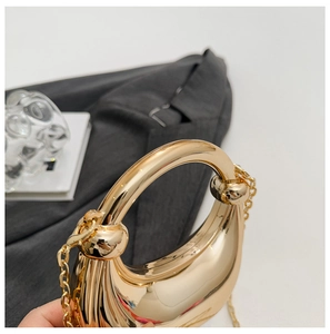 Close-up of golden crescent moon metal evening bag with circular handle and chain strap