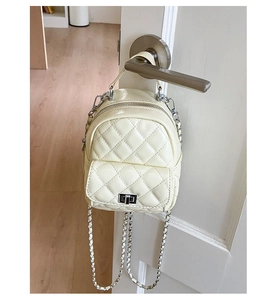 Detail of cream quilted mini backpack with silver chain strap hanging on a handle