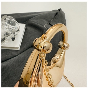 Detailed close-up of mirror gold acrylic evening bag with spherical clasp and metal chain