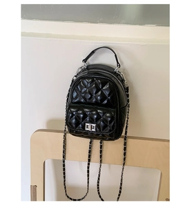 Close-up of black quilted mini backpack with silver chain strap and metal turn-lock