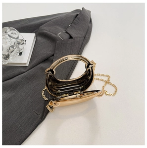 Detail of open gold metal mini evening bag with transparent acrylic and chain strap