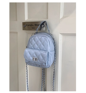 Close-up of light blue quilted mini backpack with silver chain and metal twist lock detail