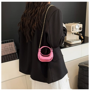 Close-up of metallic pink crescent-shaped acrylic clutch with gold chain and handle