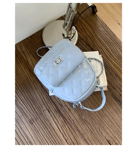 Detail of light blue quilted mini backpack featuring a silver twist-lock and metal chain strap
