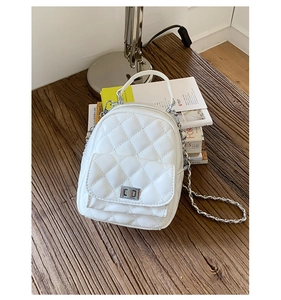 Detail of white quilted mini backpack with silver twist lock and metal chain strap