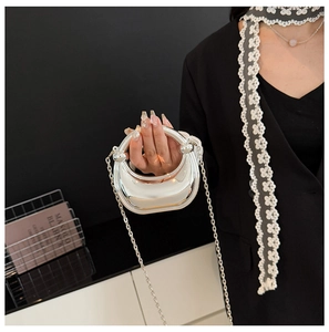 Close-up of a silver crescent moon evening bag with reflective mirror finish and chain