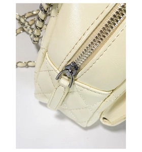 Close-up of quilted cream leather bag with silver zipper and chain strap detail