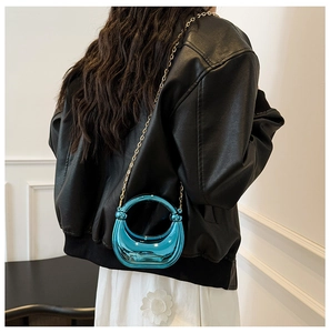 Detail of blue crescent acrylic clutch bag with shiny mirror finish and gold chain