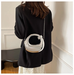 Mirror silver donut-shaped metal clutch bag with slim chain on a black blazer