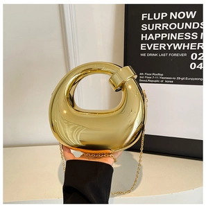 Close-up of gold mirror finish moon-shaped evening clutch bag with fine chain strap