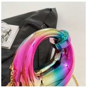 Close-up of iridescent acrylic clutch bag with metallic finish on dark blazer