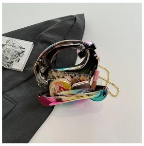 Detail of holographic acrylic Q-shaped box bag with gold chain and makeup essentials