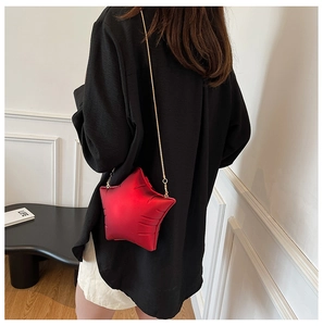 Detailed view of red star-shaped crossbody bag with gold chain strap worn by a model