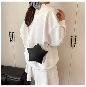 Detail of star-shaped black crossbody bag with gold chain strap and fine stitching