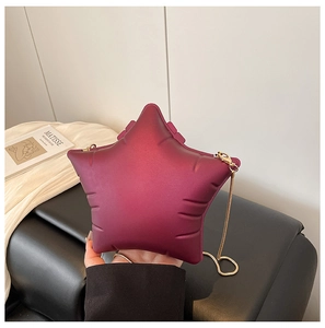 Detail of burgundy star-shaped bag featuring matte texture and gold chain strap