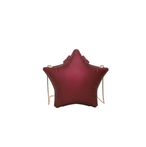Detailed view of dark red star-shaped crossbody bag with gold chain strap and embossed texture