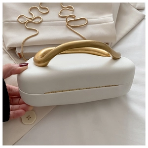 Close-up of elegant white handbag featuring a gold curved metal handle and snake chain